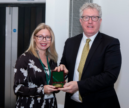 Lisa Donaldson and DCU President Prof Daire Keogh hold the award that Lisa received and smile for the camera